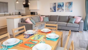 Ein moderner Wohnraum mit Essbereich, grauen Sofas und abstrakter Wandkunst.