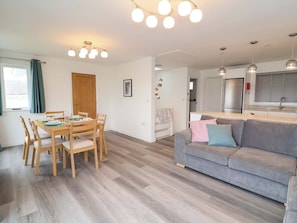 A modern living space with a dining area, a grey sofa, and a kitchen. - Belvedere (Woolacombe)