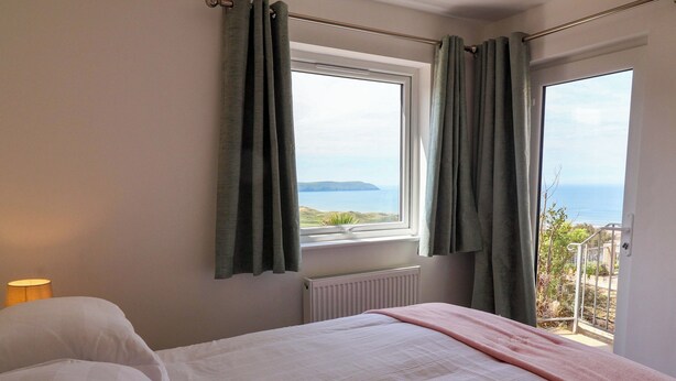 Ein Schlafzimmer mit Bett, einem Vorhangfenster, einem Heizkörper und Meerblick.