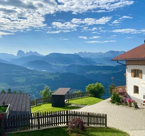 A house with a red roof, a wooden fence, and a garden with flowers. - Parndlehof Room Engel with Mountain View, Shared Terrace and Wi-Fi (Villanders)