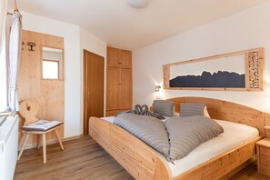 A wooden bed with pillows, a bedside table, a chair, and a wall-mounted picture. - Parndlehof Room Engel with Mountain View, Shared Terrace and Wi-Fi (Villanders)