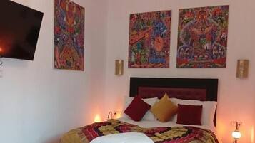 Una camera da letto con un letto, una panca, un televisore e due quadri appesi al muro.