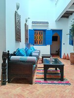 Un interior tradicional marroquí con un sofá de madera, un tapete estampado y un suelo de baldosas.
