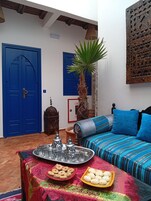 Una habitación con una cama, una mesa con comida, una palmera y puertas azules.