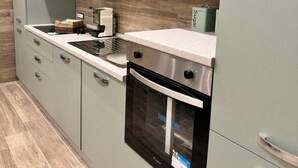 Een moderne keuken met lichtgroene kastjes, een roestvrijstalen oven en een inbouwmagneetron.'