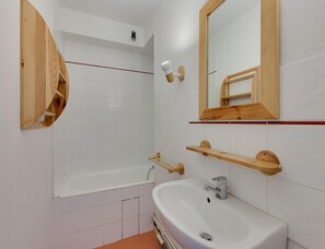 A bathroom with a white bathtub, a sink, a mirror, and wooden shelves. - Apartment in Les Deux Alpes by Ski-slopes (Les Deux Alpes)