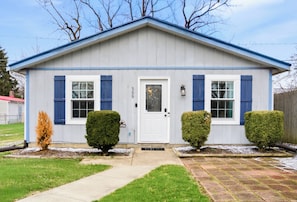 A single-story building with a white facade, blue shutters, and a front door. - Pet‑Friendly Cottage w/Grill & Patio by Lake Erie (Vermilion)