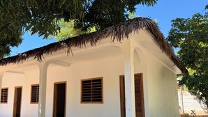 Un edificio blanco con techo de paja, varias ventanas y un acceso pavimentado.
