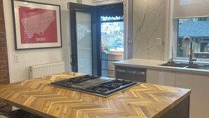 Een moderne keuken met een centraal eiland, een inbouwfornuis, een raam met uitzicht en een inlijstte kaart aan de muur.