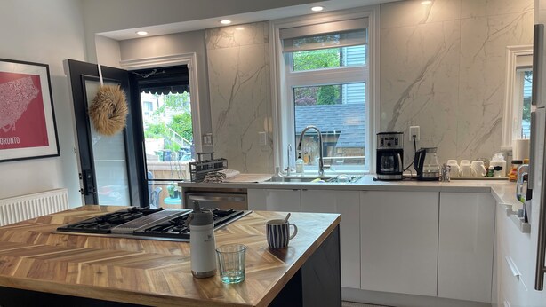 Een moderne keuken met een centraal eiland, een ingebouwde kookplaat en een raam met uitzicht op een tuin.