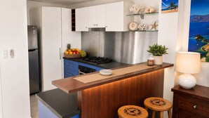 Une cuisine moderne avec des meubles blancs, une cuisinière en acier inoxydable et un comptoir-bar en bois avec des tabourets.
