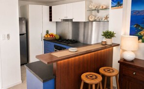 Une cuisine moderne avec des meubles blancs, une cuisinière en acier inoxydable et un comptoir-bar en bois avec des tabourets.