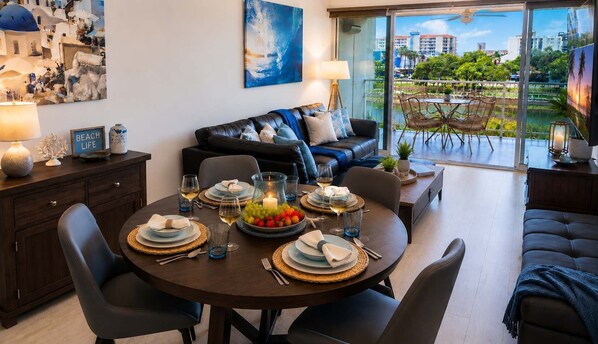 Ein Essbereich mit rundem Tisch für vier Personen, einer Couch und einem Balkon mit Blick.