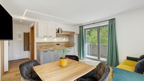 A modern kitchen with a wooden countertop, a cactus plant, and a dining area with a wooden table and chairs. - Family Apartment Nature House Bamboo – Lightness & Comfort with Mountain Views (Brennero)
