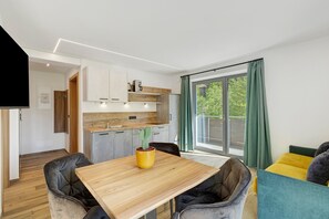 Una cucina moderna con un piano di lavoro in legno, una pianta di cactus e una zona pranzo con un tavolo e sedie in legno.