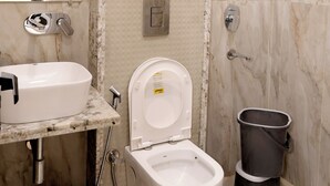 A bathroom with a marble wall, a white sink, a toilet, and a shower. - Hotel Boss In opposite New Delhi station (New Delhi)