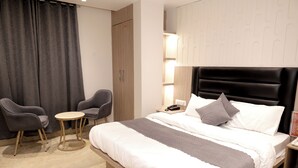 A hotel room with a bed, two armchairs, a small round table, a nightstand with a lamp, and a wardrobe. - Hotel Boss In opposite New Delhi station (New Delhi)