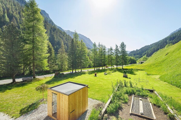 A wooden cabin with a view of a green valley and mountains.
