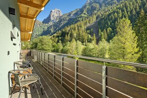 A balcony with outdoor seating, overlooking a mountainous landscape.