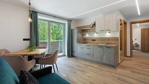A modern kitchen with a dining area, large windows, and a view of greenery. - Apartment 'Nature House Mangroves' – Peace, Sanctuary & Alpine Retreat (Brennero)