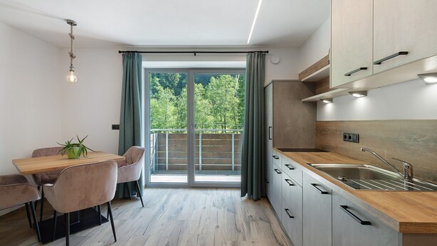 A modern kitchen with a dining area, large windows, and a view of greenery. - Apartment 'Nature House Mangroves' – Peace, Sanctuary & Alpine Retreat (Brennero)