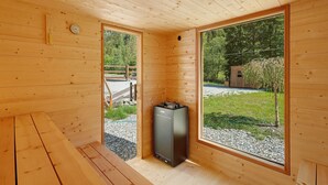 A wooden cabin interior with a sauna, large windows, and a view of the outdoors. - Apartment 'Nature House Mangroves' – Peace, Sanctuary & Alpine Retreat (Brennero)