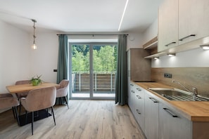 A modern kitchen with a wooden countertop, stainless steel sink, and a dining area with a table and chairs.