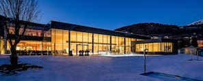 A modern building with large glass windows and a snow-covered ground. - Apartment 'Nature House Bees' – Energy, Community & a Sense of Nature (Brennero)