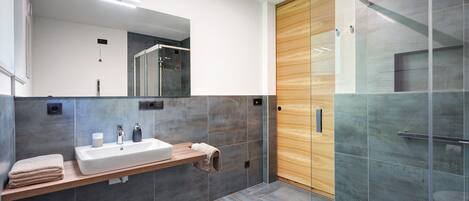 A modern bathroom with a large mirror, a sink, and a shower area.