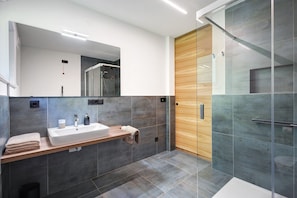 A modern bathroom with a large mirror, a sink, and a shower area. - Apartment 'Nature House Bees' – Energy, Community & a Sense of Nature (Brennero)