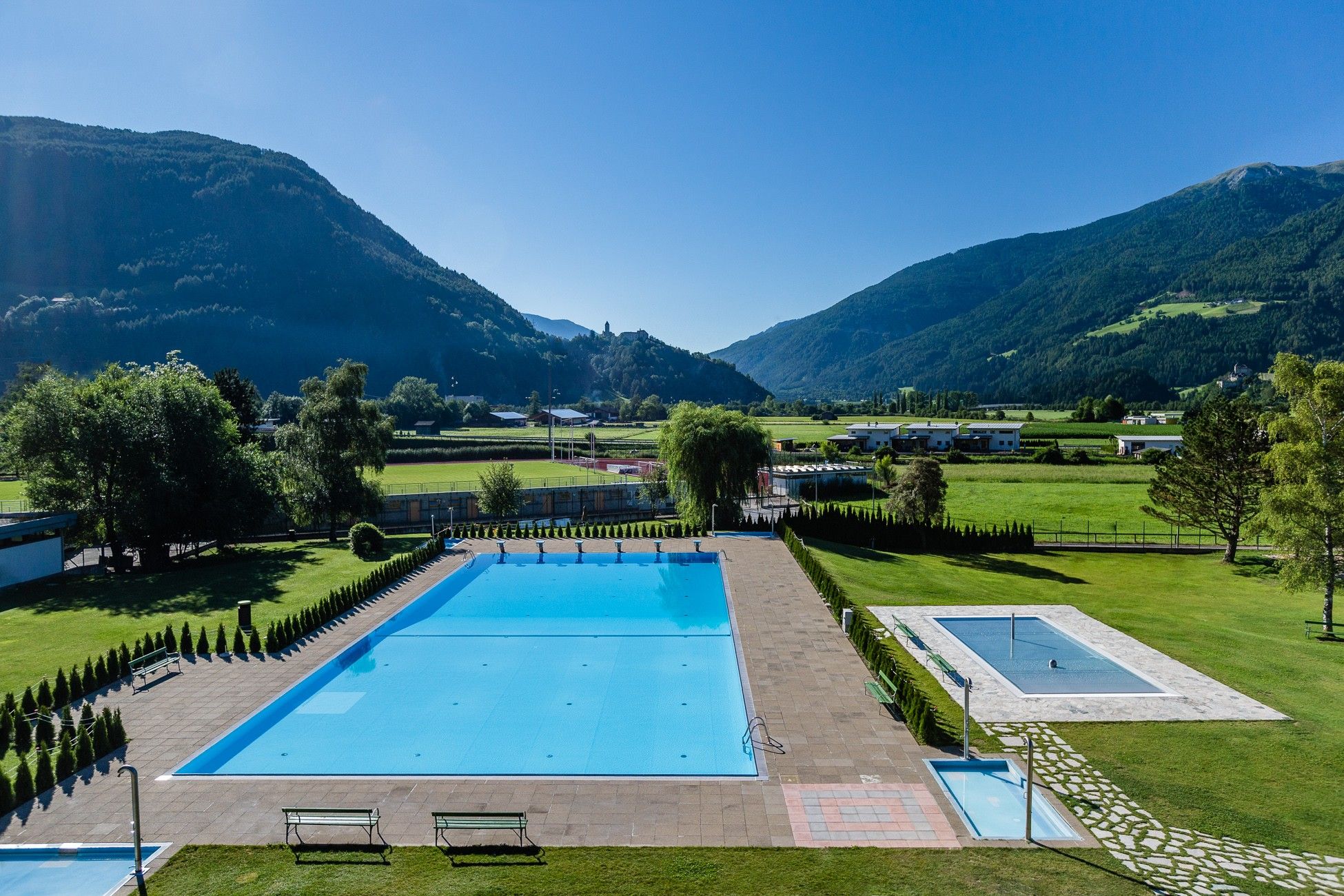 Una piscina con vistas a montañas y un edificio pequeño al fondo.
