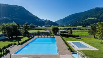 Una piscina con vistas a montañas y un edificio pequeño al fondo.
