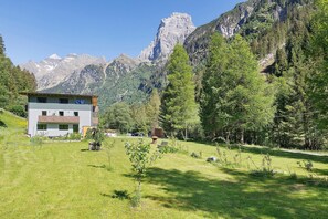 A building with a sloped roof, a grassy yard, and a mountainous backdrop.