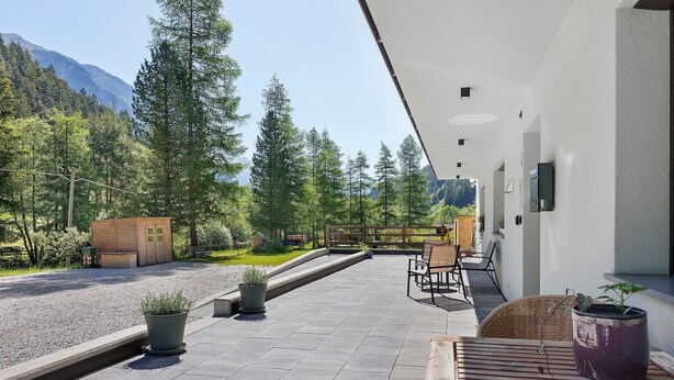 A patio with outdoor seating, potted plants, and a view of a forested area with mountains in the background. - Apartment Nature House Mushrooms – Peaceful Retreats in the Mountains (Brennero)