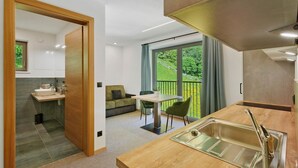 A modern kitchen with a sink, a dining area with a table and chairs, and a view of greenery outside. - Apartment Nature House Mushrooms – Peaceful Retreats in the Mountains (Brennero)