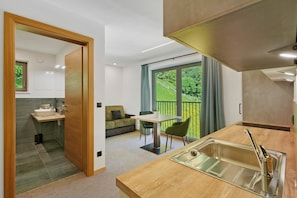 A modern kitchen with a sink, a dining area with a table and chairs, and a view of greenery outside. - Apartment Nature House Mushrooms – Peaceful Retreats in the Mountains (Brennero)