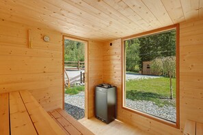 En stuga med träpanel på insidan, komplett med bastu, stora fönster och utsikt över naturen.