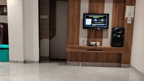 A reception area with a mounted television, a wooden counter, and a tiled floor.