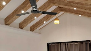 A room with a ceiling fan, a sofa with cushions, a curtain, and a light fixture.