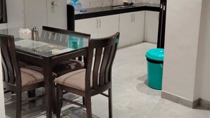 A modern kitchen with a marble backsplash, a dining table with chairs, and a water dispenser.