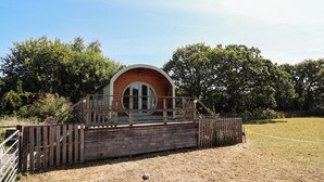 Eine Holzjagdhaus mit rundem Fenster und einer Holzdielen-Terrasse.