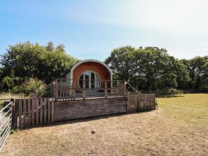 Eine Holzjagdhaus mit rundem Fenster und einer Holzdielen-Terrasse.