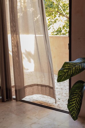Ein Zimmer mit Blick durch ein Fenster, einer Pflanze und einer Tür.
