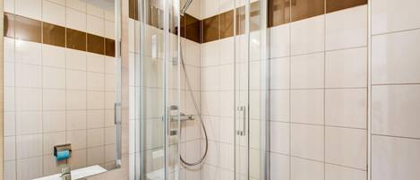 A modern bathroom with a glass shower enclosure, a white sink, and a toilet.