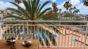 Un balcone con vista su una piscina e palme.