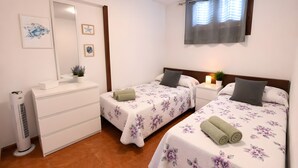 Camera d'albergo con due letti, una cassettiera, uno specchio e una ventola a soffitto.