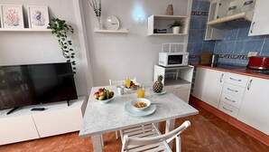 Una cucina moderna con tavolo, sedie, televisore e forno a microonde.