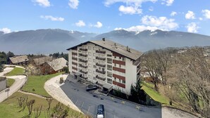 A multi-story building with balconies, a parking area, and a view of mountains. - Montana Alpine Outlook 4 Pax Panoramic Alps View (Crans-Montana)