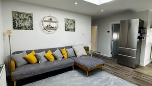 A modern living room with a sectional sofa, a glass coffee table, and a skylight. - House Sleeps 6 Garden (Mitcham)