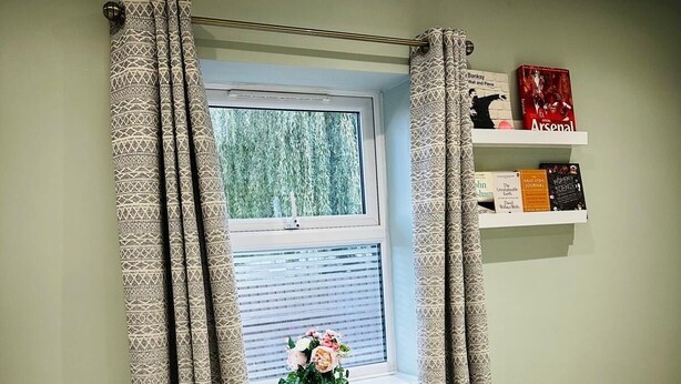 A bedroom with a window, curtains, a radiator, a shelf with books, and a bed. - House Sleeps 6 Garden (Mitcham)